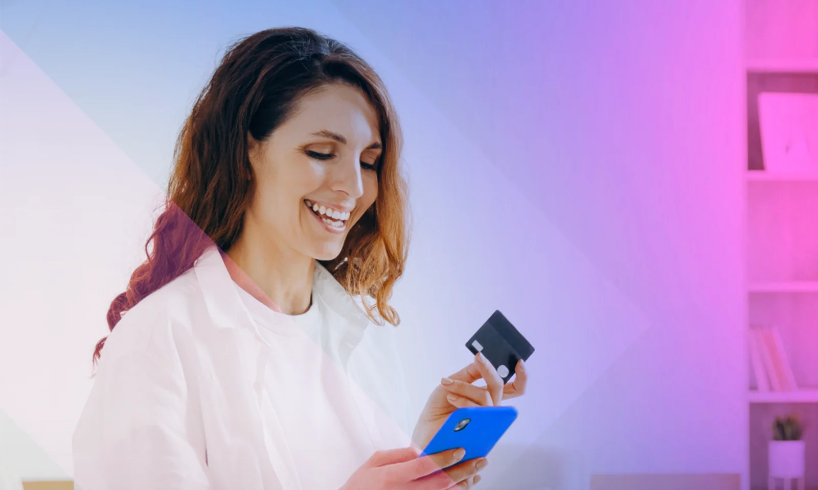 Woman smiling while using a smartphone to make an online payment, holding a credit card in her hand.