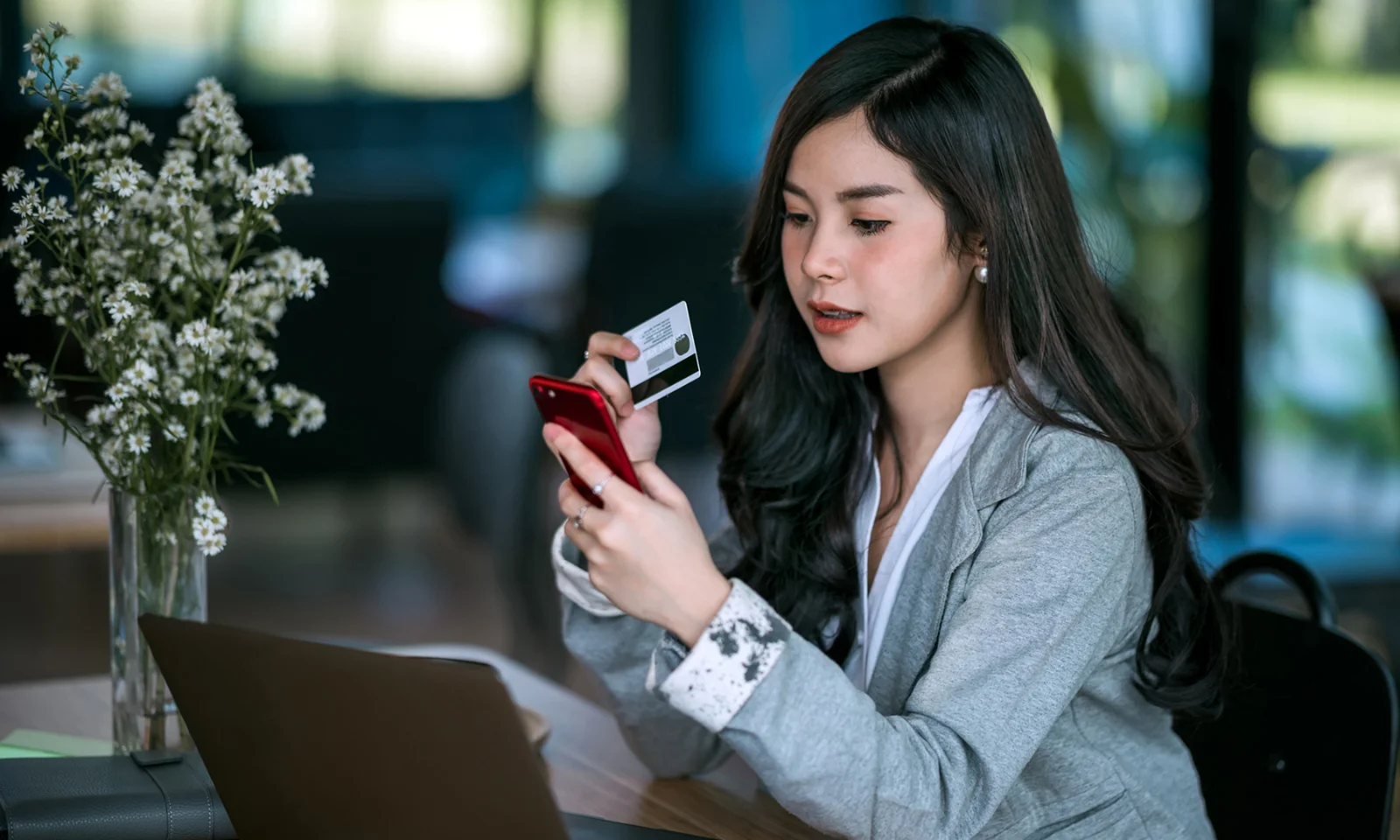 A woman using her smartphone and holding a credit card, showcasing the digital onboarding process through a mobile application.