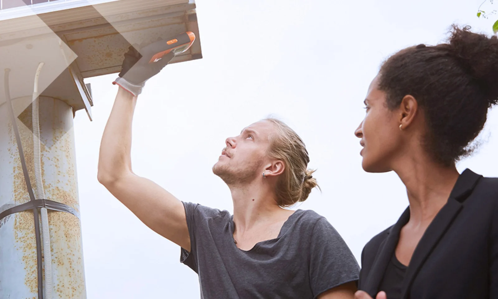 Two professionals collaborating during the installation of a solar panel, with one inspecting the panel and the other observing.