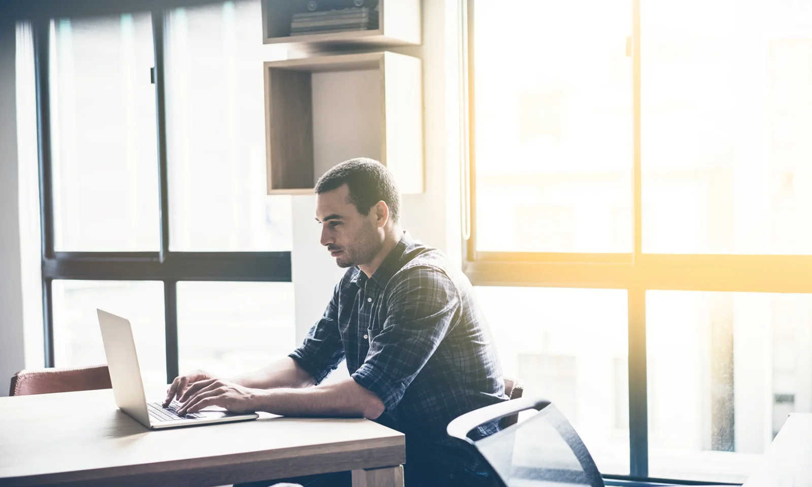 A man working on a laptop in a bright office setting, representing the redefinition of digital rights management in the modern era.