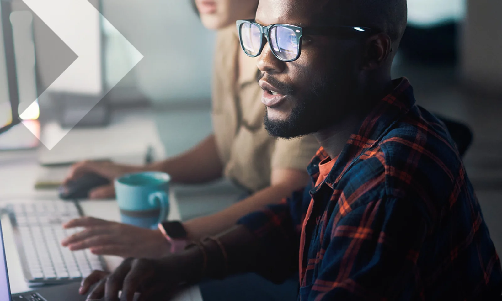 Zwei Personen arbeiten intensiv an Computern, eine Person im Vordergrund trägt eine Brille und fokussiert auf den Bildschirm. Das Bild vermittelt Professionalität und Konzentration bei der Verwaltung und Entwicklung von Anwendungen.