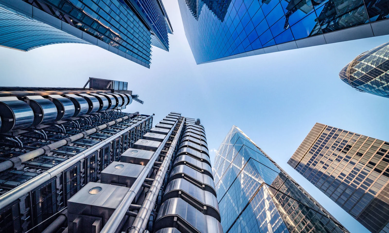 A striking view of modern skyscrapers reaching towards a clear blue sky, representing the dynamic and interconnected nature of hybrid and multicloud solutions in financial services.