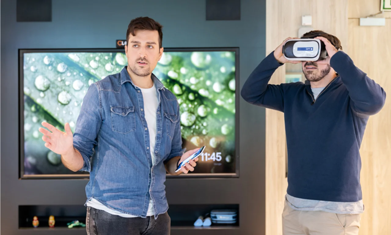 Two men in an innovation lab, one using a virtual reality headset and the other explaining or presenting something, highlighting the use of immersive technologies in modern innovation spaces.