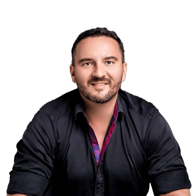 Portrait of Steffen Schacher wearing a dark shirt with a colourful inner collar, smiling with a relaxed expression.